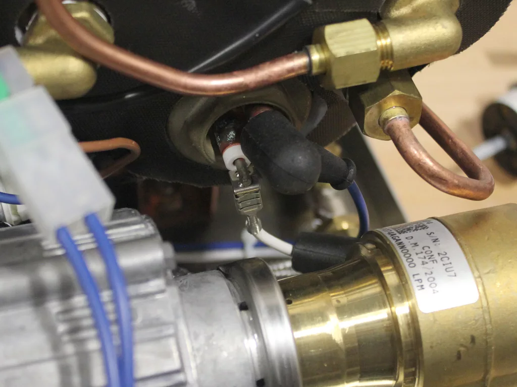Close-up of electrical and plumbing components, including copper pipes, wires with connectors, and a brass fitting—likely part of a VBM Dual Boiler’s internal mechanism or a 3.5 to 4.0 conversion process. © 2025 1st-line.com