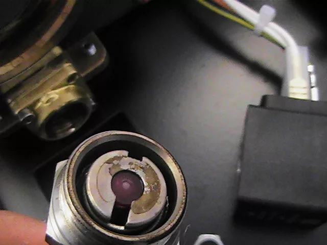 A close-up of a dirty or corroded sensor or connector in a Rancilio Silvia espresso machine, with wires and electronic components in the background, showing visible rust or residue on the metal surface. © 2025 1st-line.com