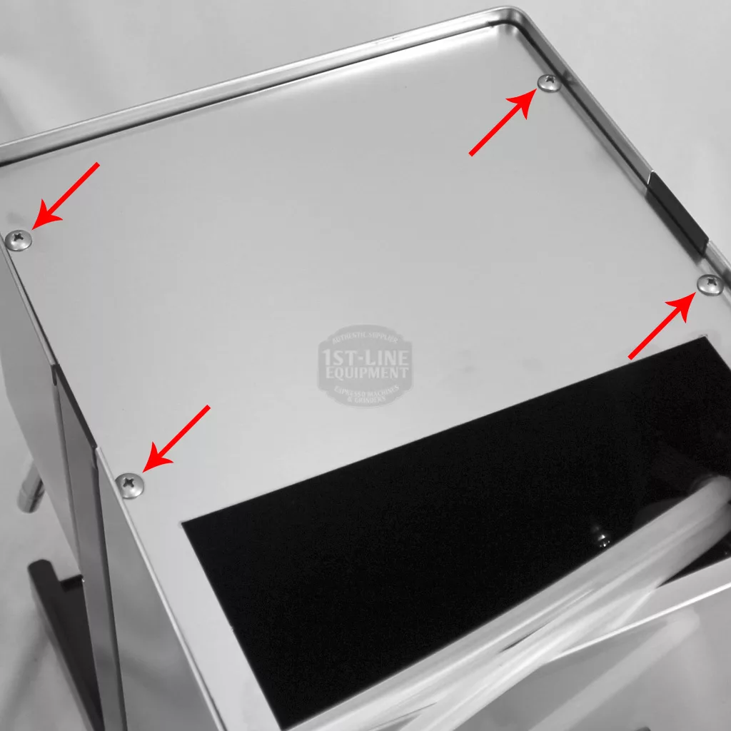 A close-up of a Rancilio Silvia machine top with four screws at the corners, each marked by a red arrow pointing to it—useful for accessing inside. There’s a black rectangular cutout and some transparent tubes on the right side. © 2025 1st-line.com