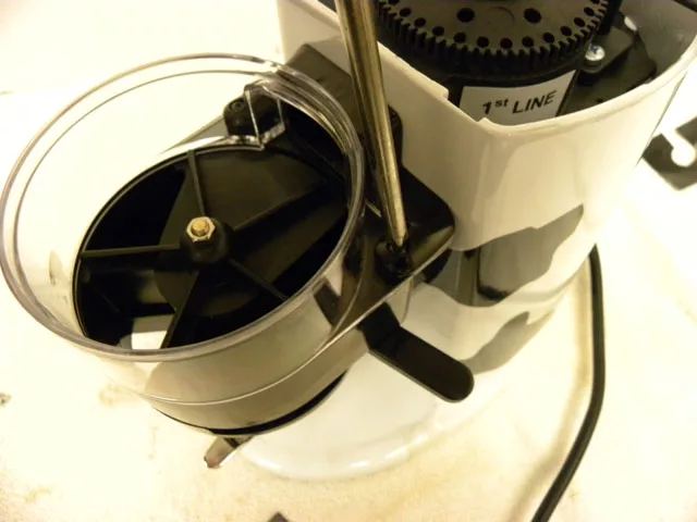 Close-up of a Rancilio electric coffee grinder, showing the hopper lid, part of the grind adjustment dial marked “1st line,” and the power cord on a light-colored surface. © 2025 1st-line.com
