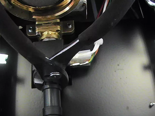 Close-up of mechanical components and wiring in a Rancilio Silvia espresso machine, including black tubing, a brass fitting, and colored electrical wires connected to a white plastic connector—ideal for OPV adjustment. © 2025 1st-line.com