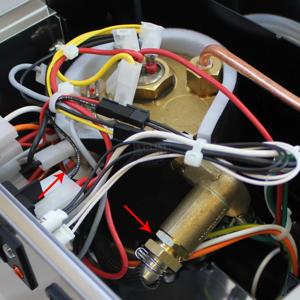 Close-up of the internal components of a Rancilio Silvia, showing wires, connectors, and a brass fitting with red arrows pointing to specific parts for identification or accessing inside during assembly guidance. © 2025 1st-line.com