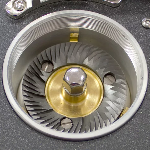 Close-up of the ECM S-Automatik 64 Espresso Grinders burr set, showcasing sharp spiral metal blades and a central bolt within a metallic circular housing. © 2025 1st-line.com