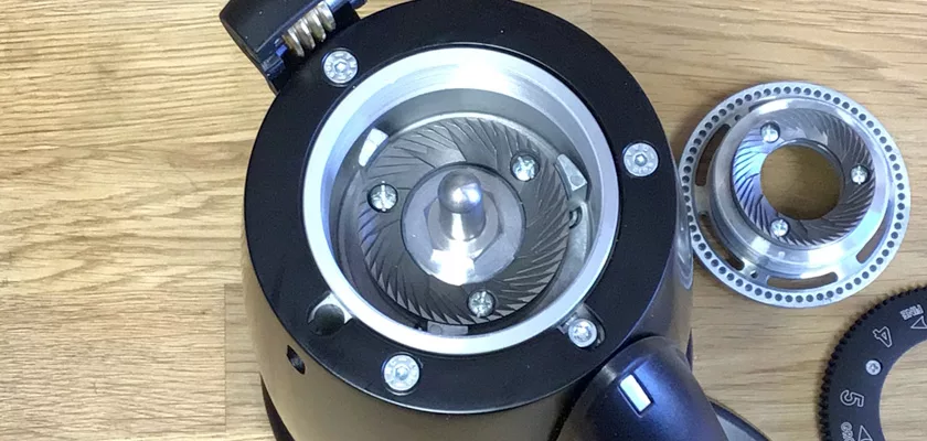 Close-up of the Elektra MSD Espresso Coffee Grinder with its top cover off, revealing the metal burrs and inner mechanisms. The grinder parts are arranged on a wooden surface, displaying key components of the MSD model. © 2025 1st-line.com