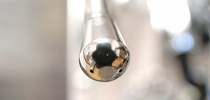 A close-up of a glass rod’s rounded end, with light reflections and distortions in the clear glass, echoes the sleek design of the DISCONTINUED ECM Mechanika V Slim Espresso Machine set against a softly blurred background. © 2025 1st-line.com