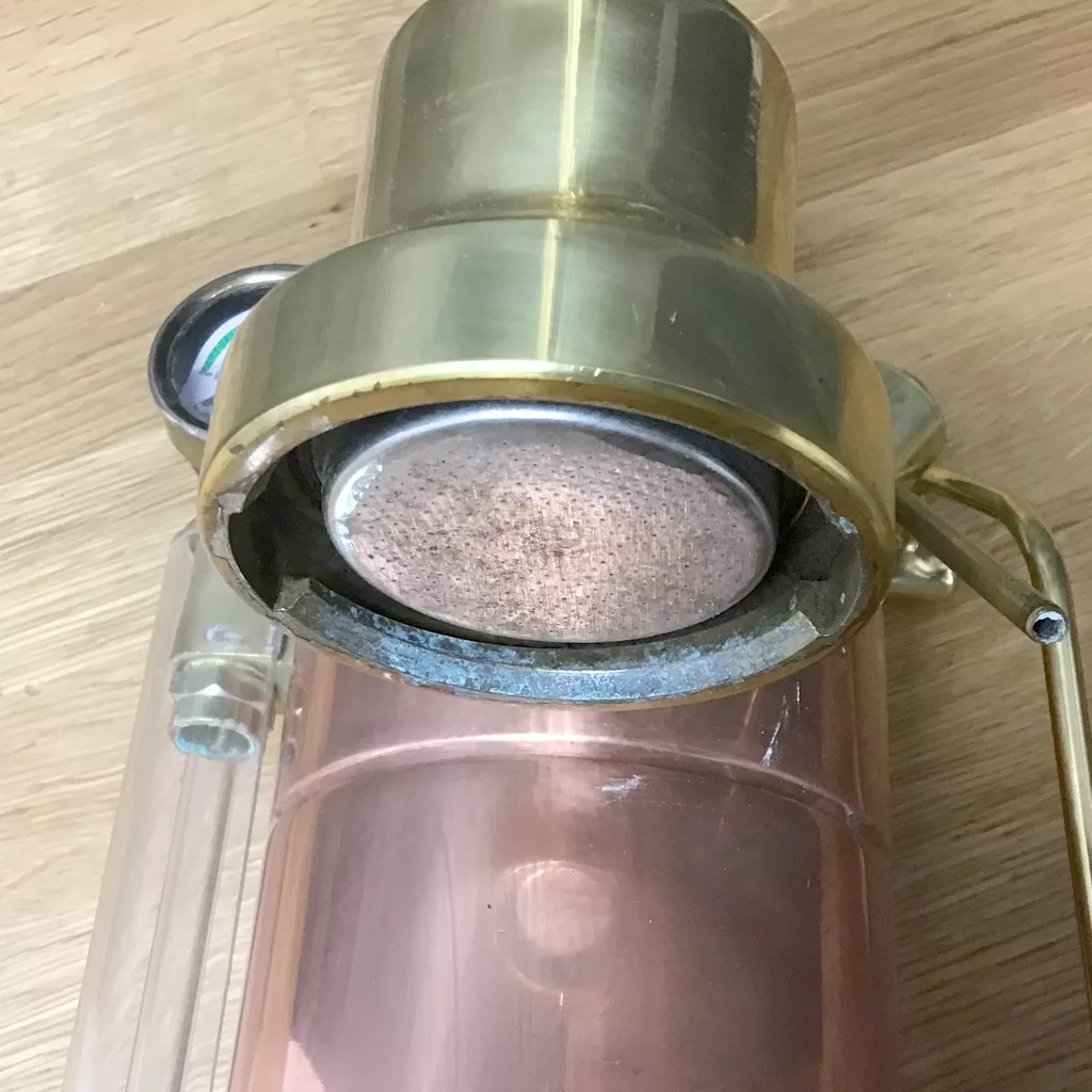 A close-up of a vintage brass and copper fire extinguisher, its worn cap and nozzle evoking the look of a (SOLD) SIDEWALK SALE - PRE-MILLENIUM La Pavoni Professional Copper & Brass Espresso Machine - 16 cup USED. © 2025 1st-line.com