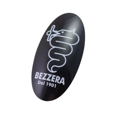 The Bezzera 5371205 Portafilter Endcap Emblem features an oval black design with a white snake wrapped around a cup above BEZZERA Dal 1901, offering a distinctive touch to your portafilter. © 2025 1st-line.com