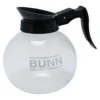 The Bunn Glass Coffee Decanter, 12 cup, 64 oz., features a clear glass body with black handle and spout, BUNN logo on the side, and is shown empty against a white background. © 2025 1st-line.com