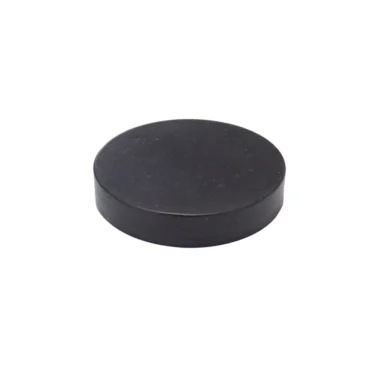 A black, round hockey puck sits on a white background. © 2025 1st-line.com