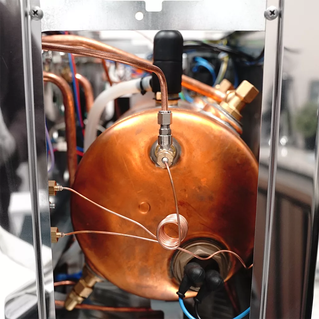 Close-up of the internal components of the discontinued Lelit PL2SVH2 Giulietta 2-Group Commercial Espresso Machine, showing copper pipes, a large copper boiler, wiring, and metal fittings inside a sturdy metallic frame. © 2025 1st-line.com