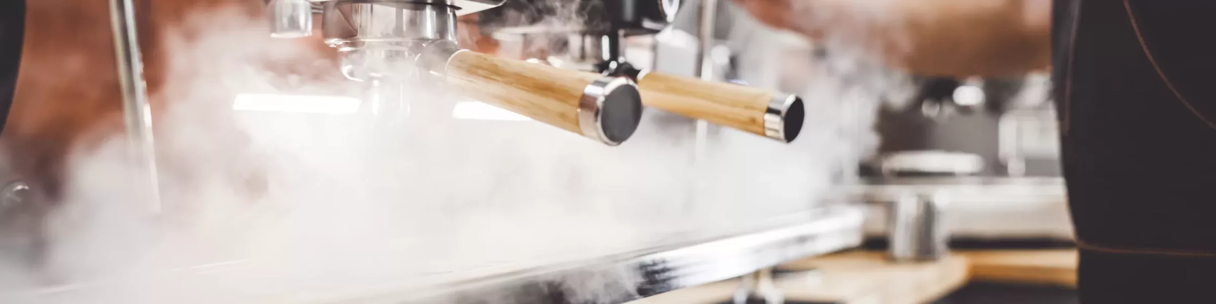 Close-up of a barista using a commercial cafe espresso machine with wooden handles, steam rising as coffee is expertly prepared. © 2025 1st-line.com