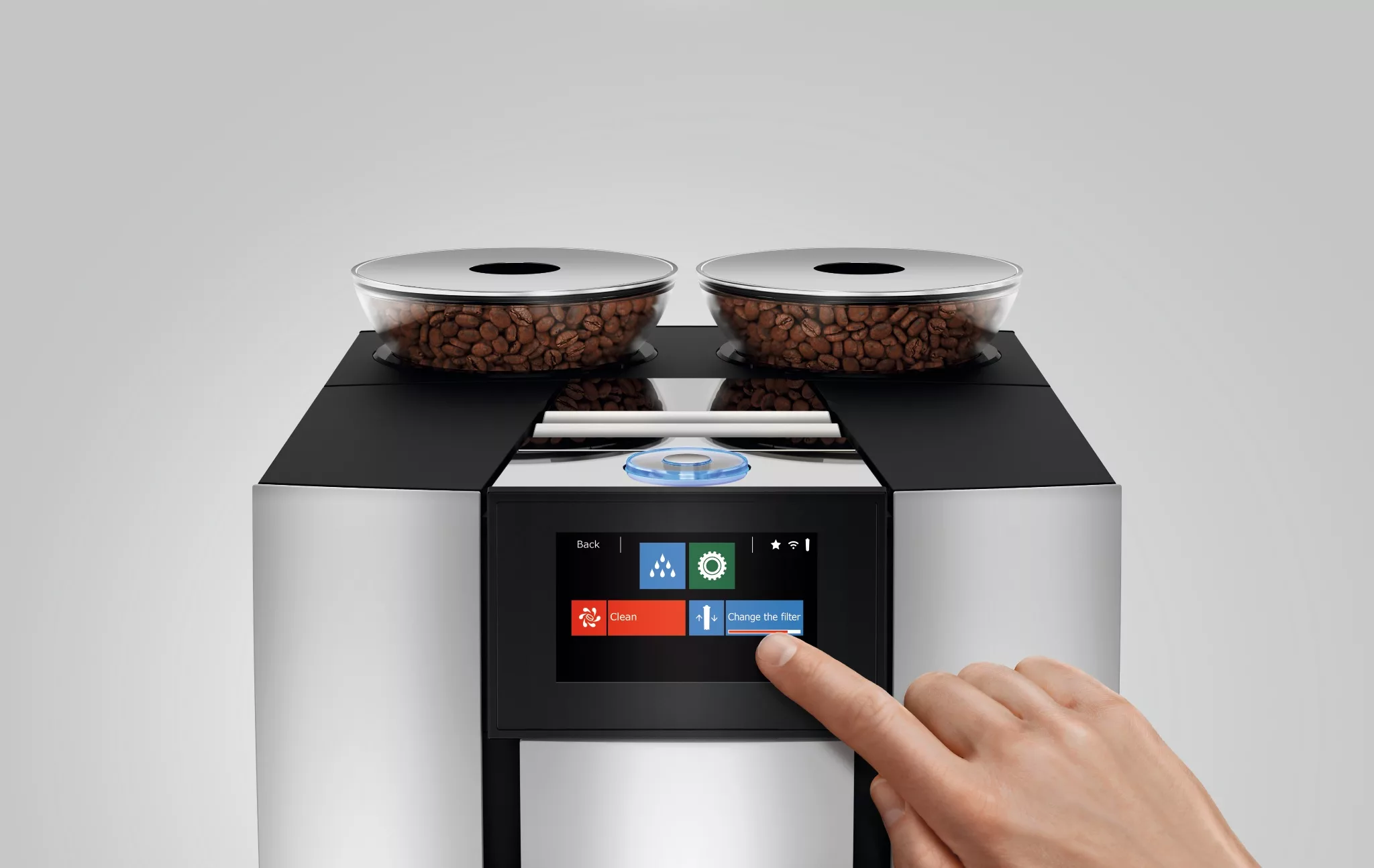 A hand selects Change the filter on the touchscreen of the DISCONTINUED Jura GIGA 6 Automatic Coffee Machine - Aluminum, featuring two coffee bean containers on top. © 2025 1st-line.com
