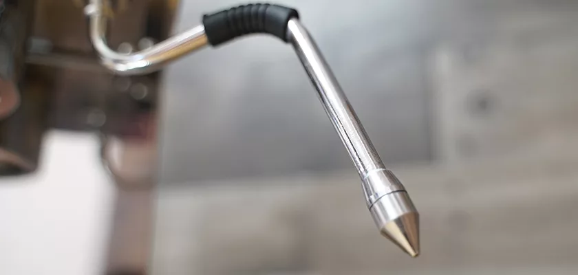 Close-up of a metal steam wand with a black grip from the DISCONTINUED Lelit Glenda PL41PLUST PID Espresso & Cappuccino Machine, designed for milk frothing, set against a blurred background. © 2025 1st-line.com
