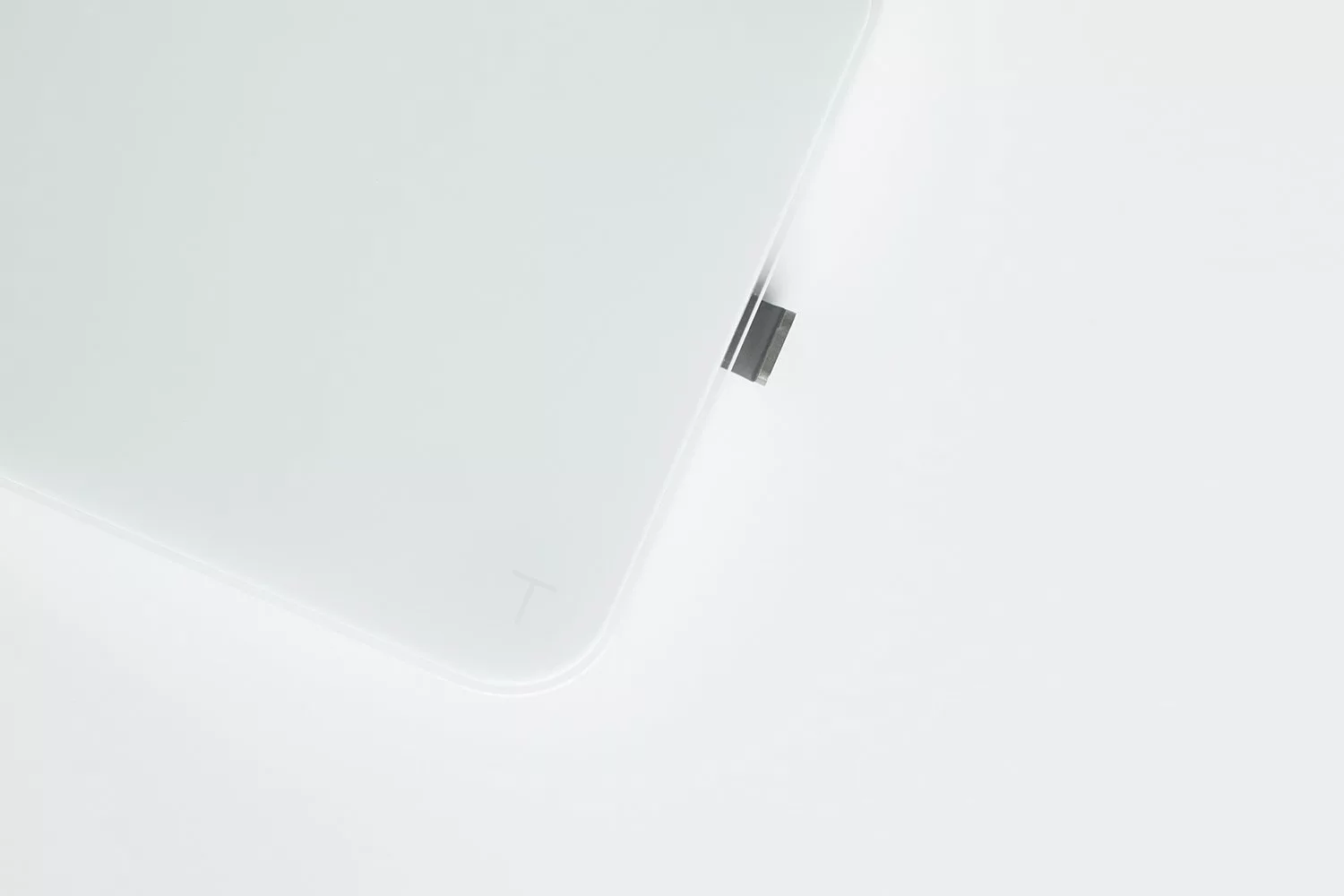 A close-up of the corner of an Acaia Pearl Model S Lock—a white, minimalist electronic device—with a small rectangular USB-C connector partially inserted, set against a plain white background. © 2025 1st-line.com