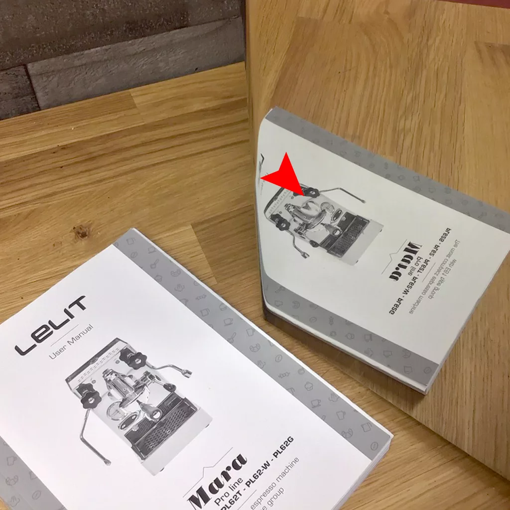 A user manual for the SOLD IN STORE PICKUP - Lelit PL62 Mara Heat Exchange Espresso Machine (returned & refurbished) rests on wood by a mirror, its reflection showing reversed text and a subtly distorted cover image. © 2025 1st-line.com