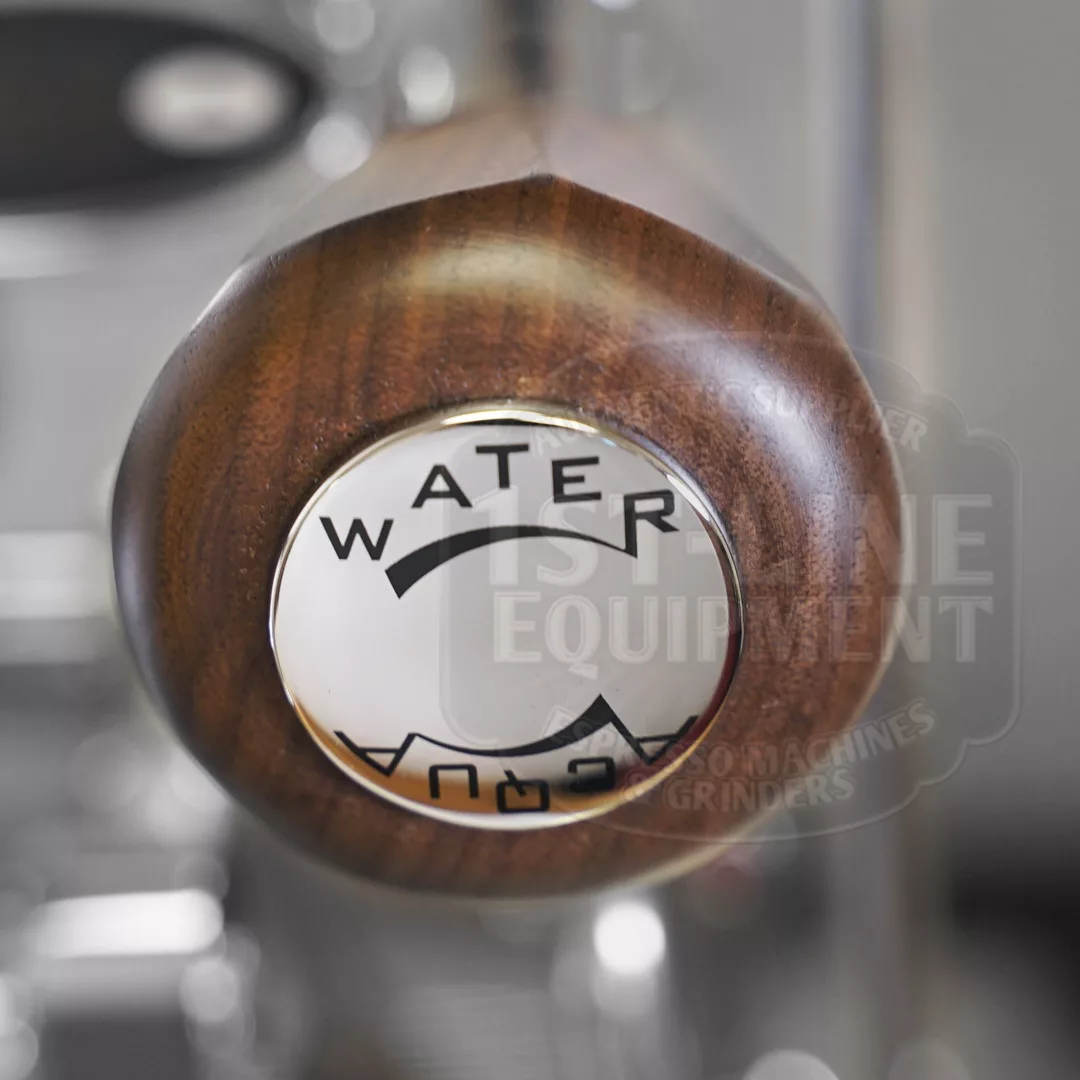 Close-up of a wooden handle with a circular metal cap labeled WATER and an arrow, likely part of the DISCONTINUED Izzo Valexia Duetto II Dual Boiler Espresso Machine. The background is blurred. © 2025 1st-line.com