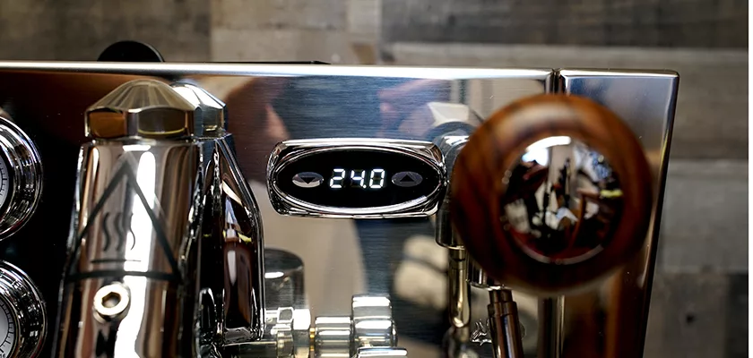 Close-up of the discontinued Izzo Valexia Duetto II Dual Boiler Espresso Machine, featuring a digital display reading “240” and a wooden handle on the right, with shiny surfaces reflecting parts of the surroundings. © 2025 1st-line.com