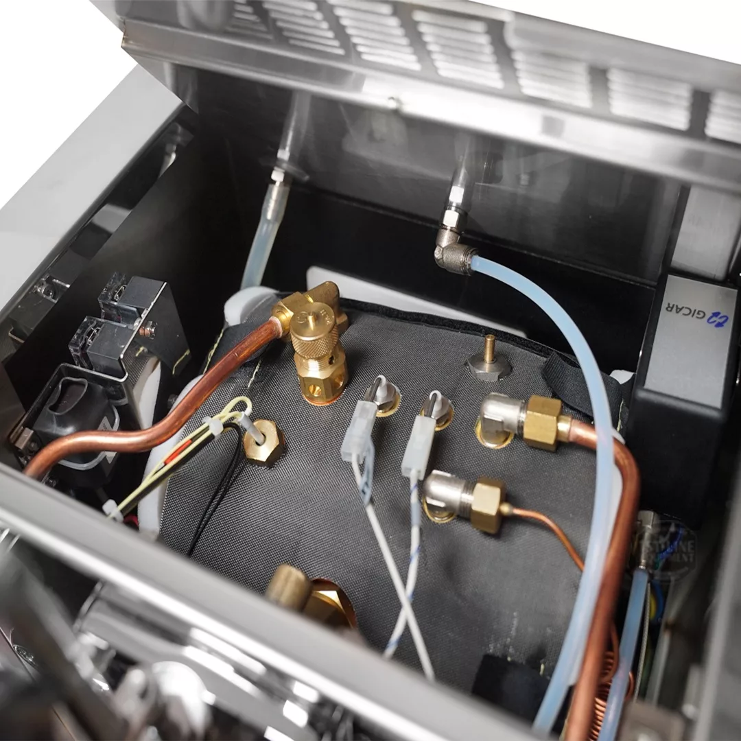 Close-up of the discontinued Izzo Valexia Leva Espresso Machine’s internal components, including copper pipes, brass fittings, insulated wiring, and a water reservoir inside its stainless steel casing. © 2025 1st-line.com