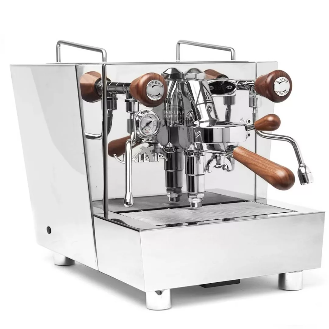 The DISCONTINUED Izzo Valexia Duetto II Dual Boiler Espresso Machine, featuring chrome finish, wooden handles/knobs, double spouts, pressure gauges, and a steam wand, is shown on a plain white background. © 2025 1st-line.com