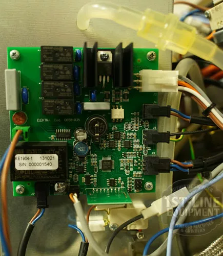 A close-up of the electronic circuit board inside the Elektra Verve Dual Boiler Espresso Machine displays relays, capacitors, heat sinks, wires, labels, and serial numbers mounted within a metal enclosure. © 2025 1st-line.com
