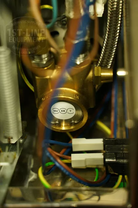 Close-up of the Elektra Verve Dual Boiler Espresso Machine’s internal components, featuring a metal valve with N, U, E, R, and T buttons amid colored wires and tubes in this advanced dual boiler system. © 2025 1st-line.com