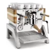 The Elektra Verve Dual Boiler Espresso Machine features a polished chrome finish, wooden handles and side panels, a top cup rack with white cups, and a front pressure gauge showcasing its dual boiler performance. © 2025 1st-line.com