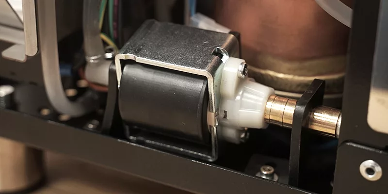 Close-up of an electric solenoid valve attached to a brass pipe with visible wiring and metal components, as found in the Bezzera Crema DE HX Espresso Machine. © 2025 1st-line.com