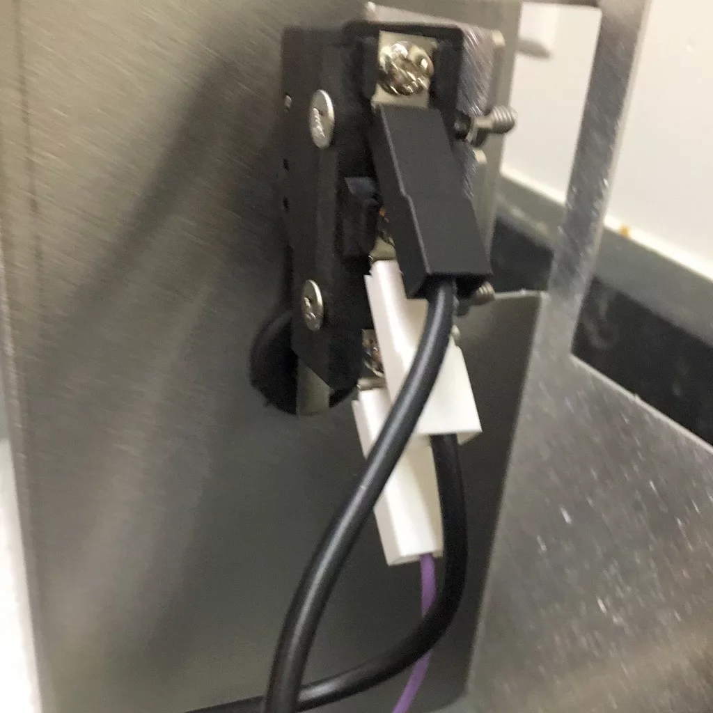 Close-up of an electrical connector mounted on a metal surface inside a VBM Super HX espresso machine, with black and white wires plugged in. The connector is secured with screws, and a purple wire is also visible among the cables. © 2025 1st-line.com
