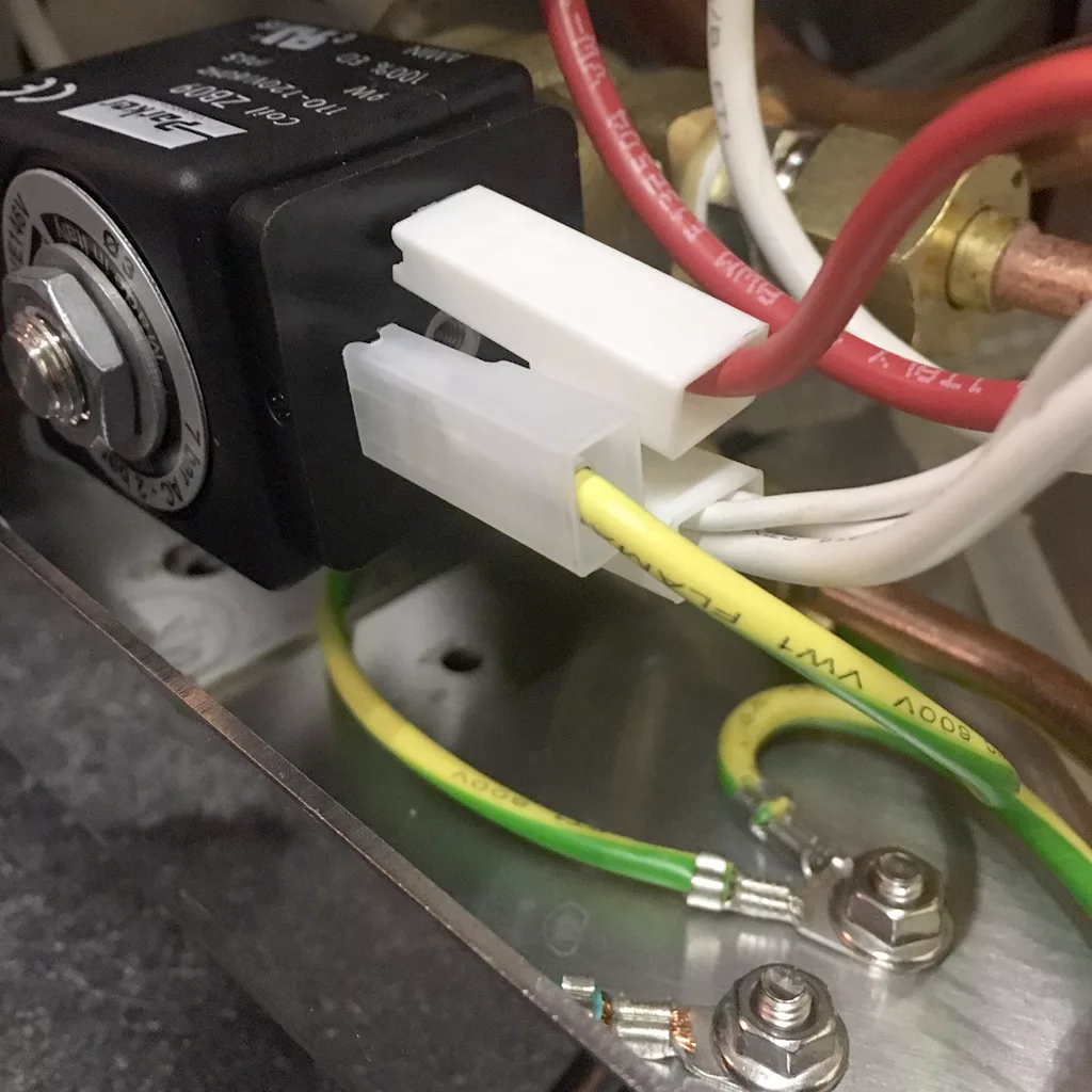 Close-up of electrical wiring connected to a terminal block inside an espresso machine, with red, white, yellow, and green wires attached to a metallic surface. Two screw terminals are visible in this VBM Super HX tank only setup. © 2025 1st-line.com