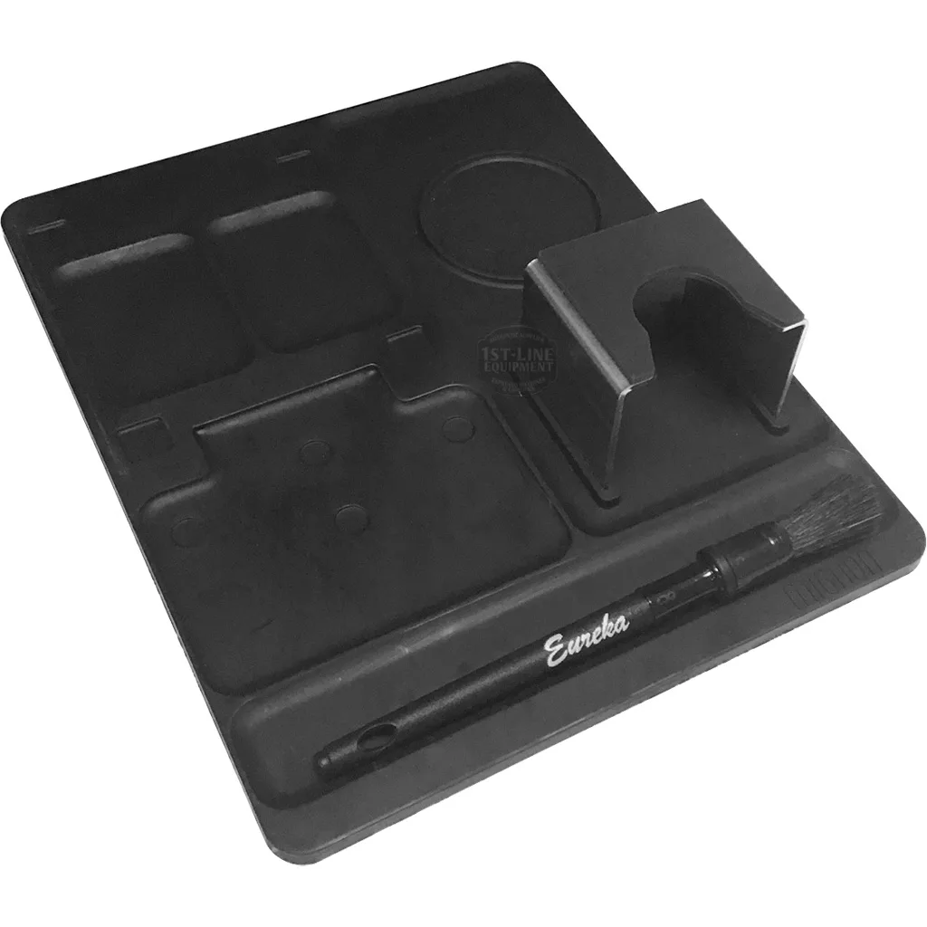 The Eureka 2311.0117KIT Mignon Multi-Purpose Mat is a black silicone mat for espresso machines, with compartments, a portafilter slot, and a groove for an Eureka Mignon brush. © 2025 1st-line.com