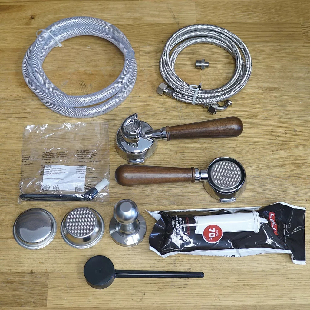 Assorted coffee machine accessories—wooden-handled portafilters, metal baskets, tamper, hoses, and more—ideal for upgrading your Lelit Bianca Dual Boiler Espresso Machine V2 PID with manual brew pressure profiling DEMO model. © 2025 1st-line.com