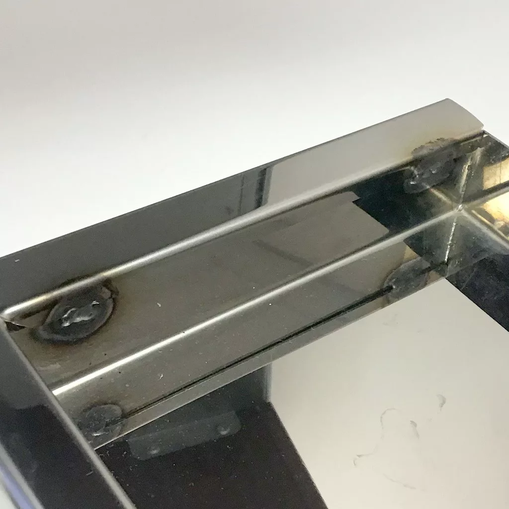 Close-up of a SOLD USED ECM M3024.4 Drip Tray with round edges, showing the corner where glass and metal meet. Visible weld marks on the metal, reflections, and a clean minimal background are highlighted in the image. © 2025 1st-line.com