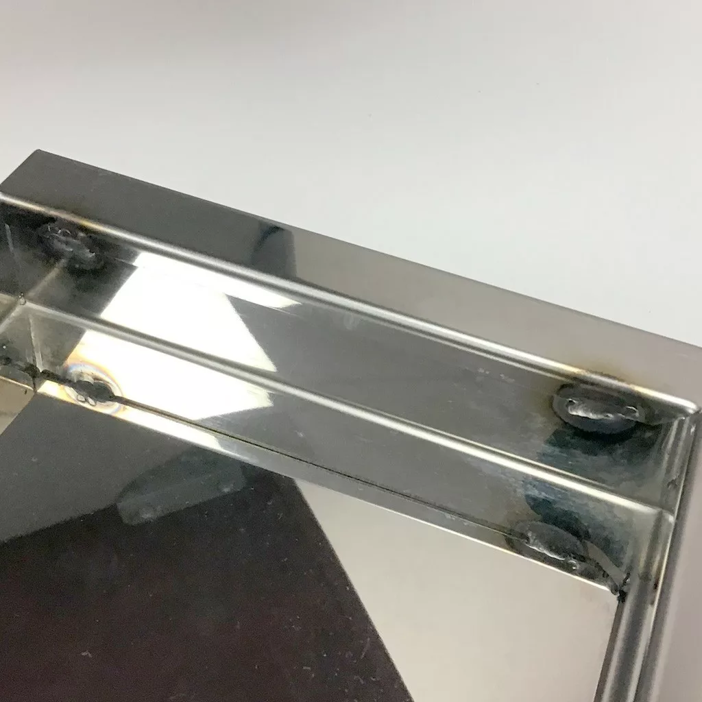 Close-up of the SOLD USED ECM M3024.4 Drip Tray with round edges, showing shiny metal corner joint, weld marks, and reflections against a white and dark background. © 2025 1st-line.com