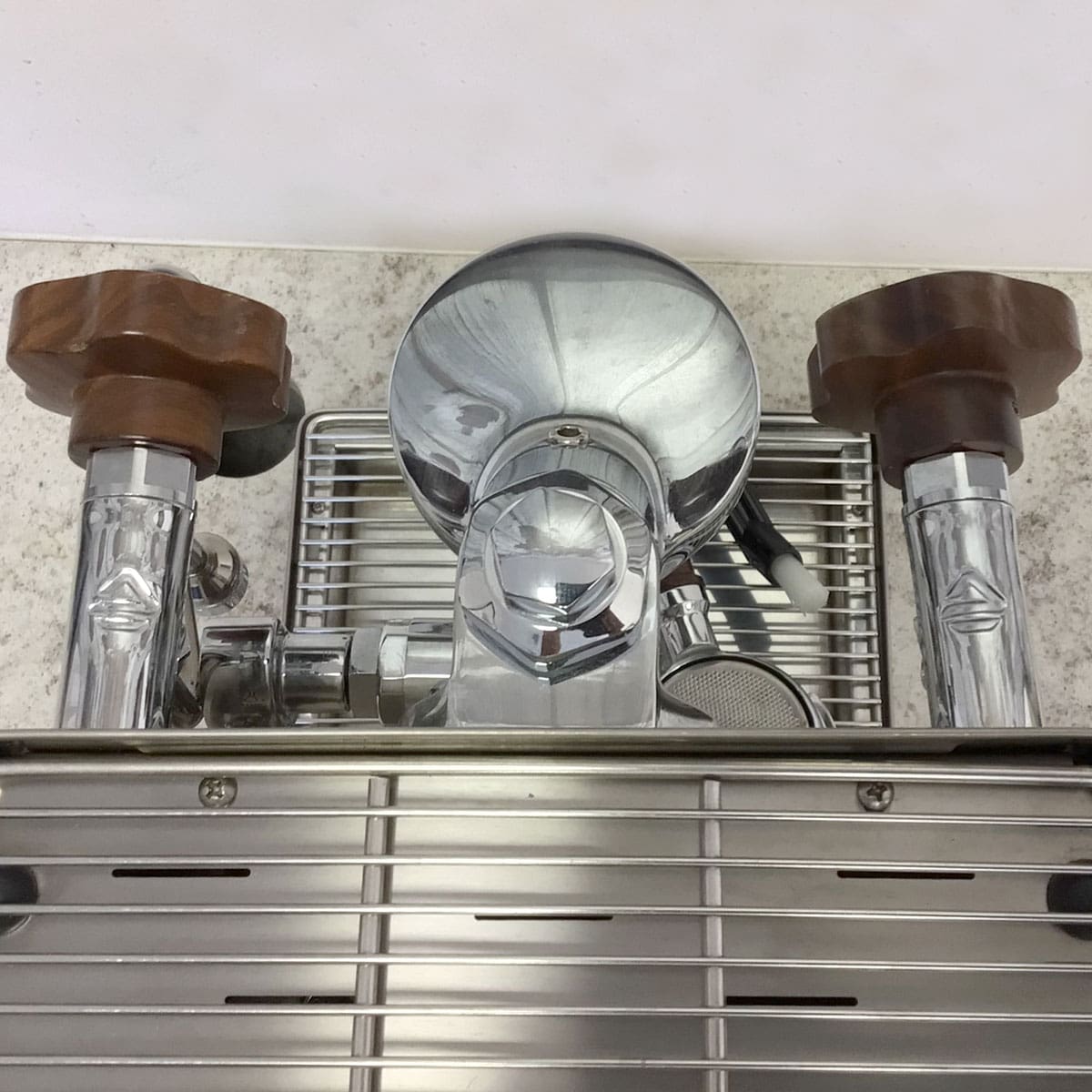 Close-up of a used SIDEWALK SALE - Lelit Mara X PL62X HX Espresso Machine (E213), featuring two brown handles, a central pressure gauge, and a metal drip tray, viewed from above on a speckled countertop. © 2025 1st-line.com