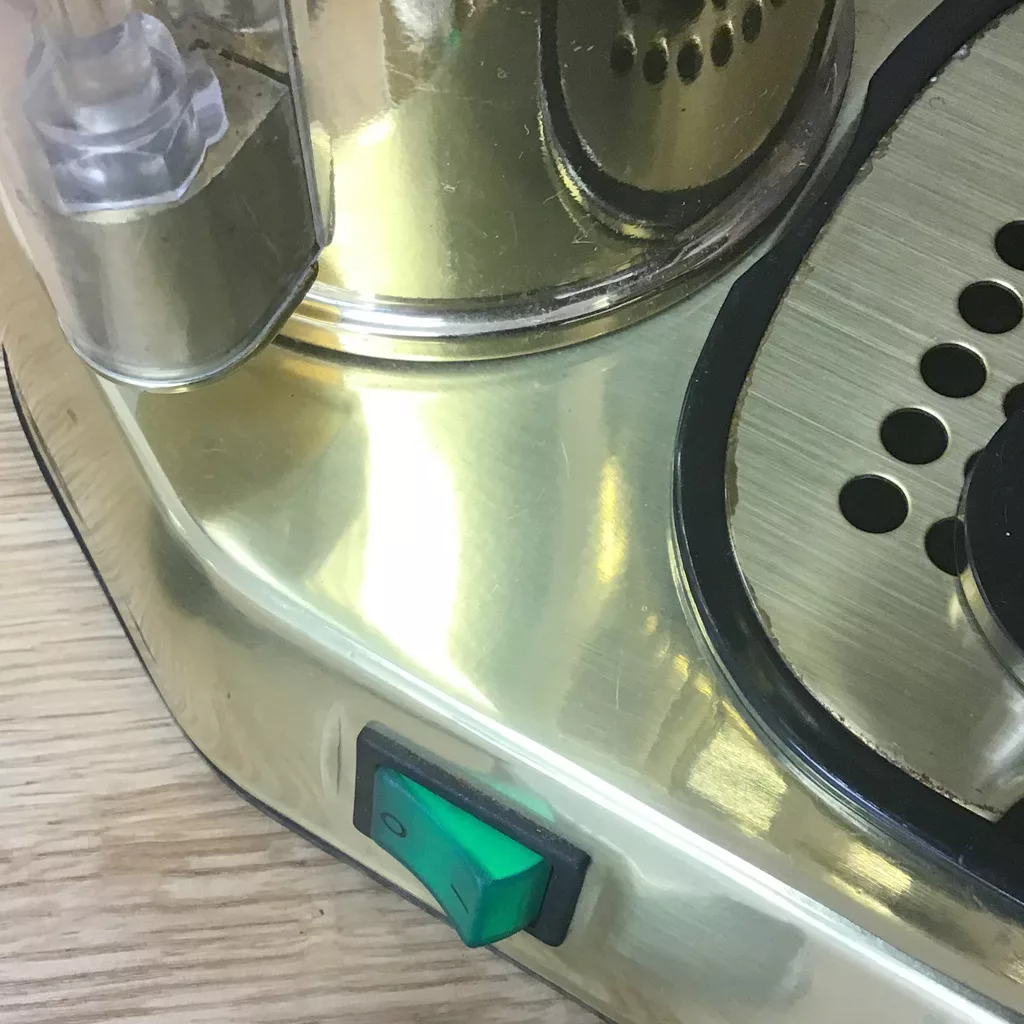 Close-up of the SOLD IN STORE PICKUP ONLY USED La Pavoni 16-Cup Professional Brass Lever Espresso Machine, featuring a gold finish, green power switch, steam wand, and metal drip tray on a wooden surface with classic brass accents. © 2025 1st-line.com