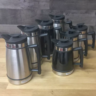 Six SIDEWALK SALE - Planetary Design French Press Coffee Makers USED with black lids, handles, and bases are displayed on a wooden surface before a grey wall. Each French press is labeled PROPERTY. © 2025 1st-line.com