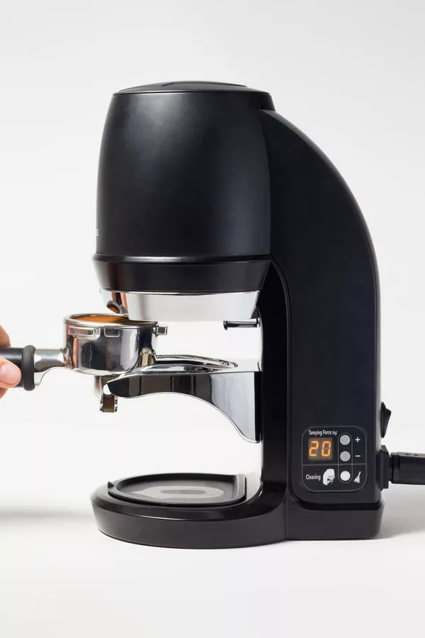 A DISCONTINUED PUQPress Q2 (Stand Alone) Precision Coffee Tamper (53-58.3mm) in black, featuring a digital display reading 20 and a hand inserting a portafilter, is shown against a plain white background. © 2025 1st-line.com