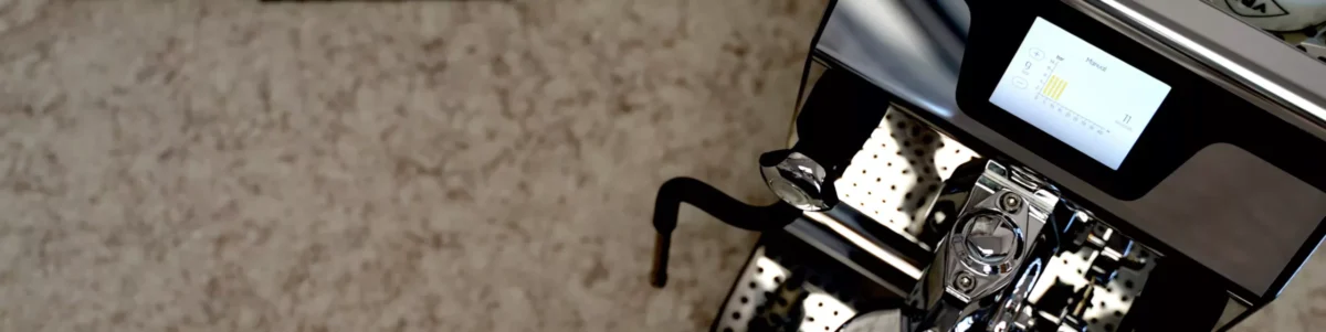 Close-up of a modern dual boiler espresso machine with a digital display screen and metal drip tray, set against a speckled countertop background. Only part of the machine is visible in the frame. © 2025 1st-line.com