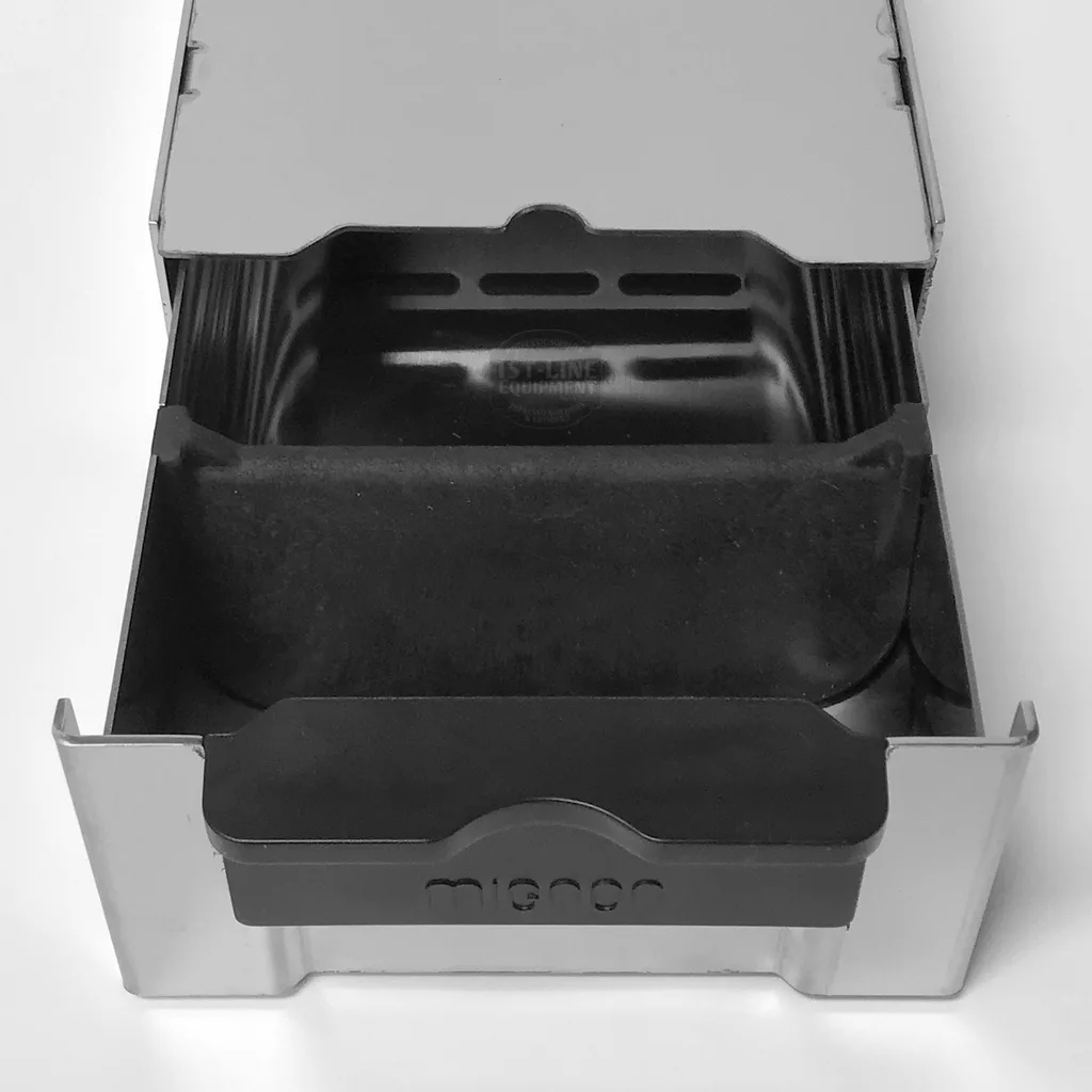 The Eureka 2311.0119A0R01-901 Mignon Base/Knockbox, made of metal and plastic, sits under espresso machines to collect used coffee grounds. Micro is embossed on the front panel and it is viewed from above. © 2025 1st-line.com