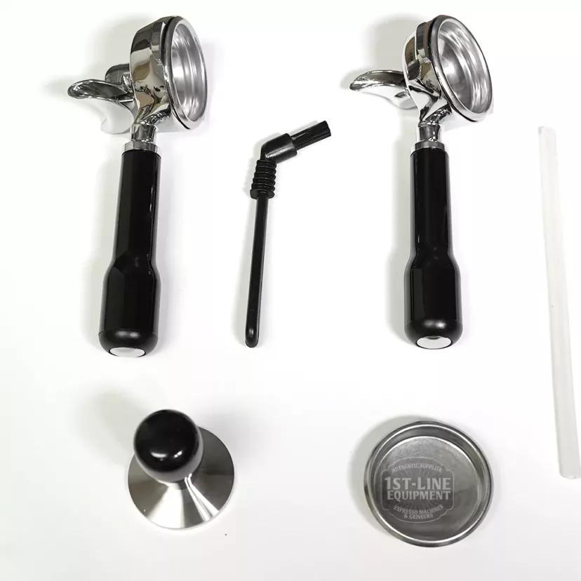 Essential accessories for your SOLD OUT - Profitec Pro 300 Dual Boiler Espresso Machine—including two portafilters, a cleaning brush, metal tamper, branded metal lid, and white plastic stick—are neatly displayed on a white background. © 2025 1st-line.com