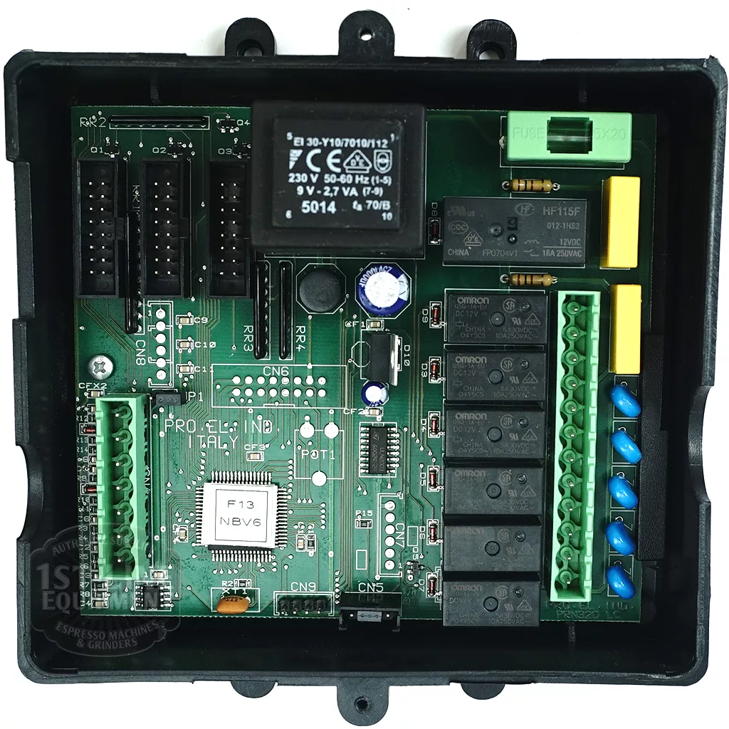 The Pro. El. Ind. A1500095 Brain Unit – SDE3D F13 NBV6 is an electronic control board in a black rectangular case labeled “Proelind Italy,” with relays, connectors, circuit components, and multiple ports for wiring connections. © 2025 1st-line.com
