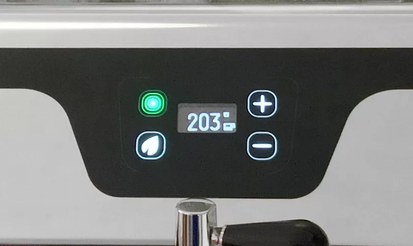 The VBM Junior Digital HX Espresso Machine w/ Flow Control features a 203° digital control panel with illuminated plus/minus buttons, a green power light, flow control, and a leaf symbol on the display. © 2025 1st-line.com