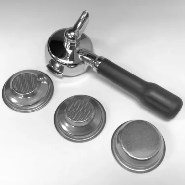 A Lelit PLA585S 58 mm Single Spout Black Handle Portafilter rests on a white surface beside three metal filter baskets—two with visible fine mesh screens and one upside down, revealing its solid base. © 2025 1st-line.com