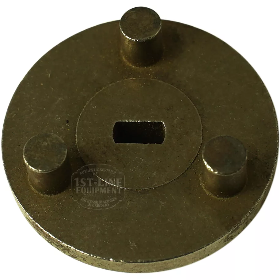 A worn brass tool with three cylindrical pegs and a central rectangular slot, designed for espresso machine maintenance tasks such as servicing the F..601 PUMP CONNECT FLANGE. © 2025 1st-line.com