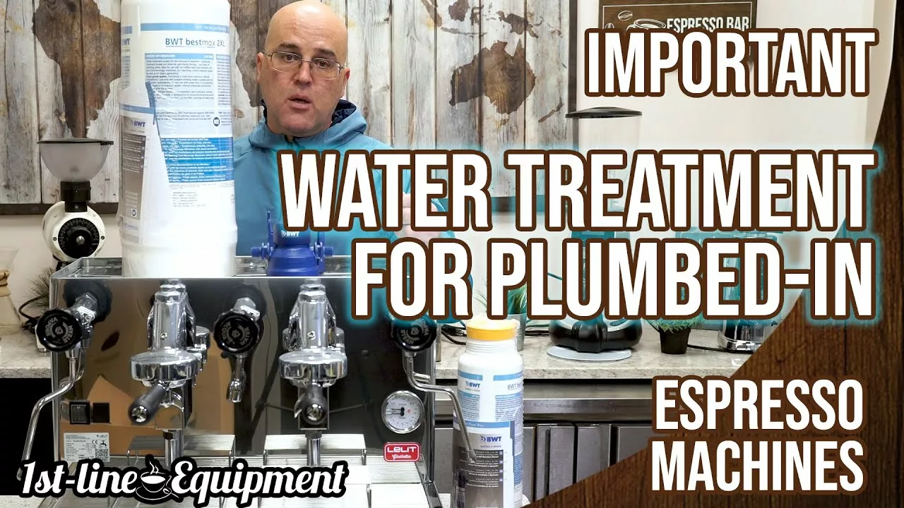 A man stands behind a countertop with espresso machines, holding a large water filter. Text reads: IMPORTANT WATER TREATMENT FOR PLUMBED-IN ESPRESSO MACHINES. The 1st-line Equipment logo is at the bottom. © 2025 1st-line.com