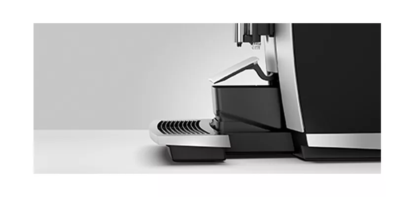 Close-up side view of the discontinued Jura GIGA 6 (NAA) Automatic Espresso Machine in black and silver on a white countertop, showing the drip tray and cup platform. © 2025 1st-line.com