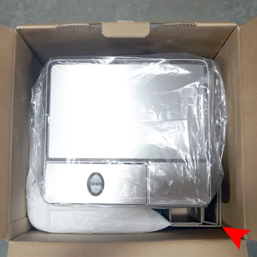 A Lelit Elizabeth stainless steel appliance, still wrapped in protective plastic, sits inside an open cardboard box with packaging materials around it. A red arrow points to the bottom right corner. © 2025 1st-line.com