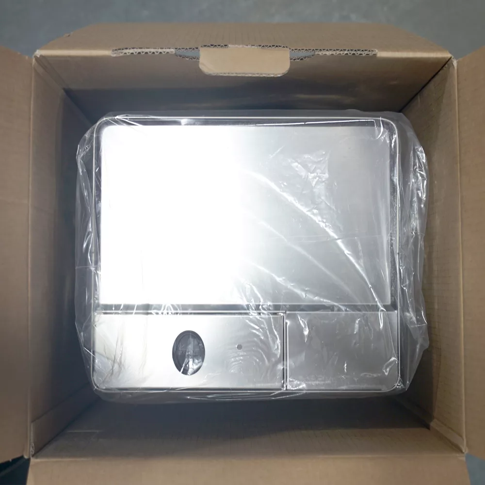 A stainless steel appliance, possibly a toaster oven or microwave, is wrapped in plastic packaging and packed inside a cardboard box. © 2025 1st-line.com