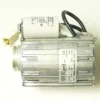 A Wega W80151 230V 120W START MOTOR in silver features a white top-mounted capacitor, black and blue wires, and a white connector. Specs are labeled on the casing; the item is shown against a light background. © 2025 1st-line.com