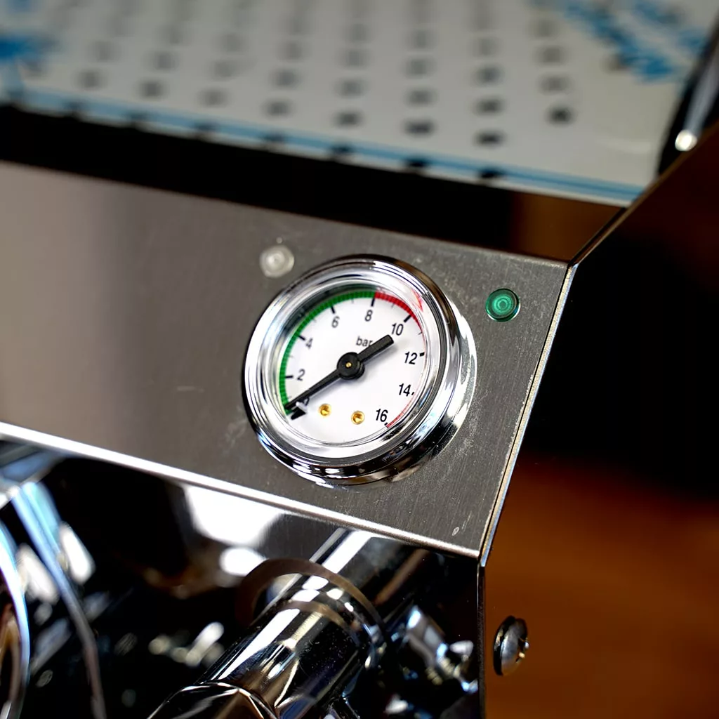 Close-up of a pressure gauge on the SIDEWALK SALE - VBM Domobar Super HX Tank Espresso Machine DEMO (E114), showing a dial with green, yellow, and red sections, plus a small green indicator light. © 2025 1st-line.com
